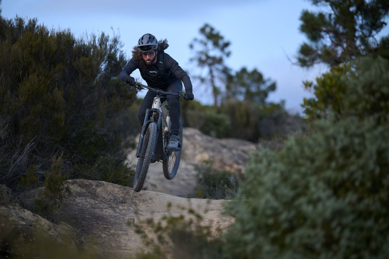 Jezdec na Giant Stance E+ skáče na trailové stezce